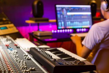Kayıt stüdyosunda çalışan Asyalı profesyonel yapımcının arkasında konsol fader 'ı karıştırmaya odaklan. müzik üretim konsepti