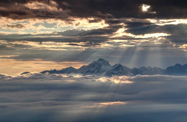 Zářící sluneční paprsky osvětlují zasněžených Julských Alp a moře mraků — Stock fotografie