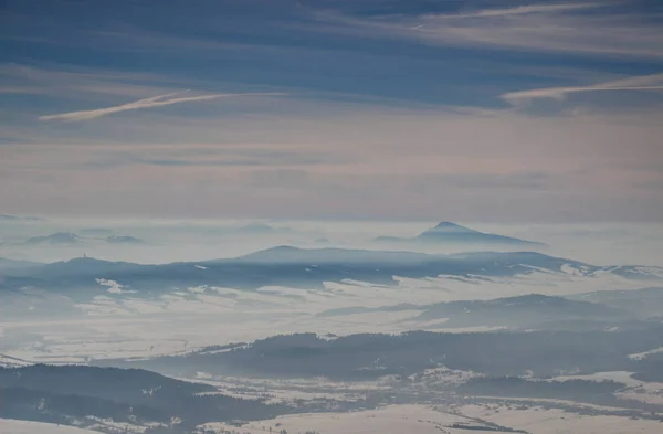 Prosluněné modré hřebeny, mlhavá údolí pod mrak pruhy v zimě — Stock fotografie