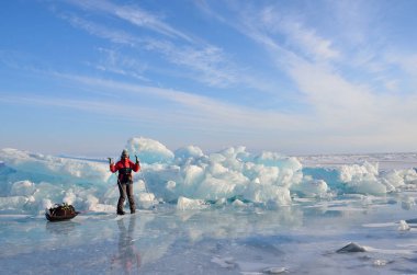 Baikal lake, Russia, March, 01, 2017. Traveler with a sledge-drag going in front of the ice ridges near the village of Bolshie Koty at lake Baikal clipart