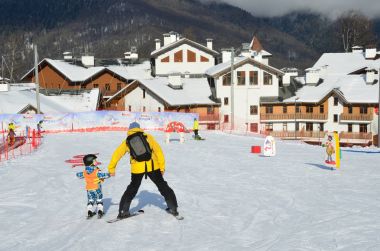 Posa Khutor, Sochi, Rusya Federasyonu, Ocak, 26, 2018. Kayak Merkezi Rosa Khutor, Olimpiyat Köyü arka planda çocuğun eğitim yamaçta Kayak yapmaya küçük çocuk öğretim dersi
