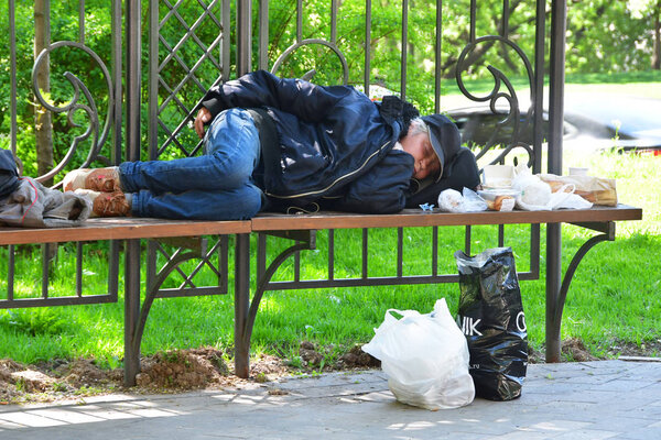 Moscow, Russia, May, 08, 2018. Homeless sleeping on a bench on Plyuschikha street in the spring in Moscow