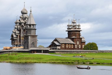 Kizhi, Karelia, 25 Ağustos 2015. Dönüşüm Kilisesi (Preobrazhensky Katedrali), Bakire Pokrovsky Katedrali 'nin Şefaat Kilisesi) ve antik çan kulesi yakınlarındaki bir teknede balıkçı.