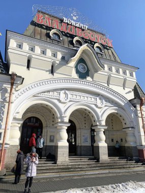 Vladivostok, Rusya, Mart, 05: 2020. İnsanlar ilkbaharda mavi gökyüzüne karşı tarihi tren istasyonunun yakınında yürüyorlar.