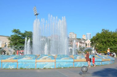 Vladivostok, Rusya, 31 Ağustos 2017. İnsanlar yazın Vladivostok 'taki spor sehpasında güzel bir çeşmenin yanında yürüyorlar.