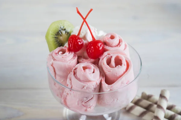 Rolls of  Strawberry ice cream. Fresh fried berry ice cream, ice roll on the light wooden background.