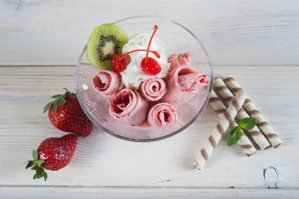 Rolls of  Strawberry ice cream. Fresh fried berry ice cream, ice roll on the light wooden background.