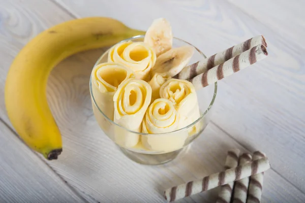 Rolls of banana ice cream. Fresh fried fruit ice cream, ice roll on a light wooden background.