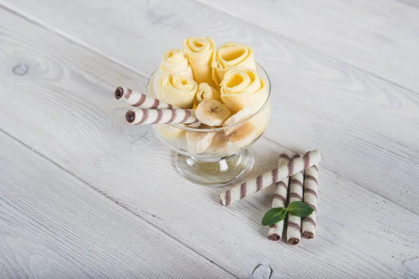 Rolls of banana ice cream. Fresh fried fruit ice cream, ice roll on a light wooden background.