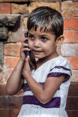 BHAKTAPUR, NEPAL  AUGUST 13, 2018: Unidentified Newari Nepalese child with mobile phone in Bhaktapur, Nepal, listed as a World Heritage by UNESCO for its rich culture, temples, and wood artwork