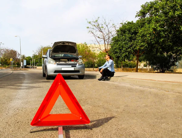 A woman with a broken car, she waits for assistance In the middle of the street