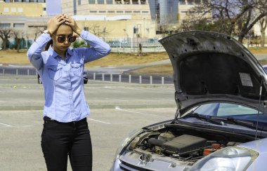 Kırık arabası olan bir kadının kafasını yardım için bekler tutar