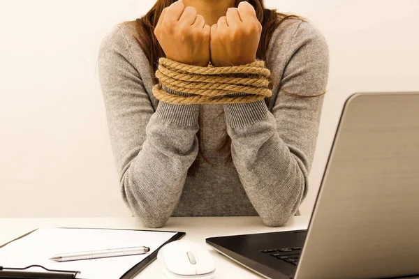 Una mujer con un portátil en la oficina con las manos atadas con una cuerda — Foto de Stock