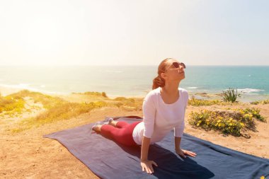 Sağlıklı yaşam için deniz sahilde bir genç kadın yoga