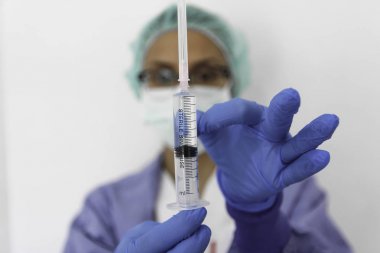 Doktor hemşire eldivenli bir şırınga tutar