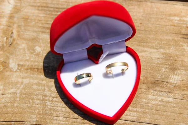 Una caja roja de terciopelo con un par de anillos de boda de oro — Foto de Stock