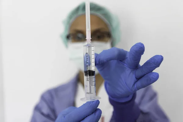 Doktor hemşire eldivenli bir şırınga tutar