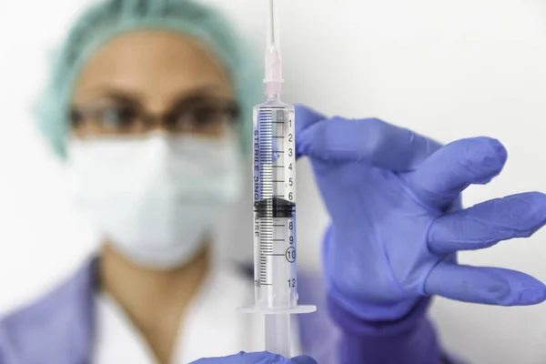 Doktor hemşire eldivenli bir şırınga tutar