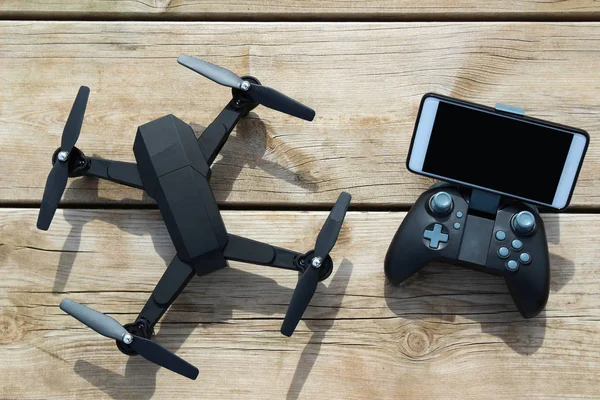 Drone quadcopter bir uzaktan kumanda ve ahşap masa telefonu ile siyah