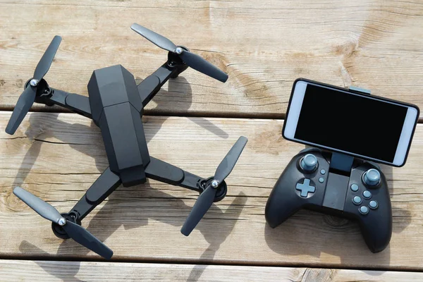 Drone quadcopter bir uzaktan kumanda ve ahşap masa telefonu ile siyah