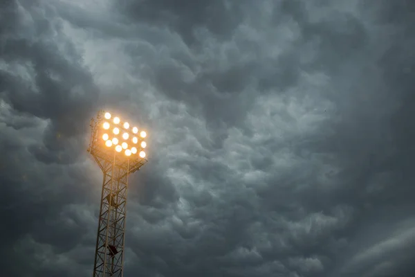 Tour de projecteur sur fond de ciel sombre. Mât avec projecteurs illuminent sur fond de stade et ciel nocturne — Photo