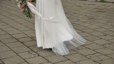 Gelinlik giymiş beyaz gelinlikli kız eski şehirde yürüyor. Yüzü yok, kapat.