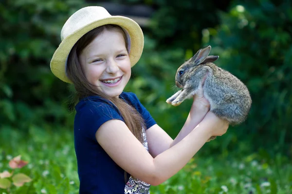 Chica está sosteniendo un pequeño conejo — Foto de Stock