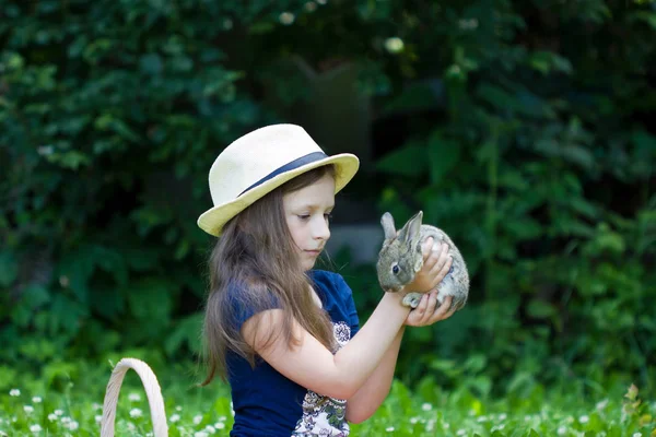 Chica está sosteniendo un pequeño conejo — Foto de Stock