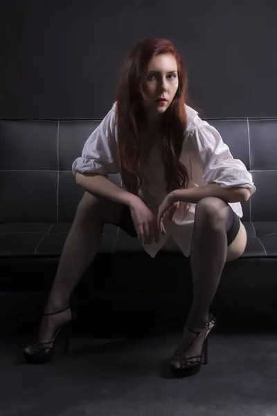 Mulher sexy no sofá de couro preto — Fotografia de Stock