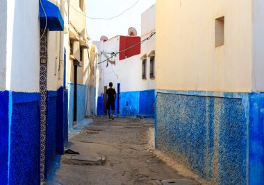 Küçük sokaklar mavi ve beyaz kasbah içinde yürüyen adam