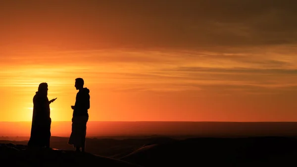 Sylwetka mężczyzn stojących na pustyni o zachodzie słońca — Zdjęcie stockowe