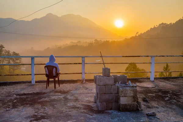 Person enjoying the sunrise view of forest and mountains, summer