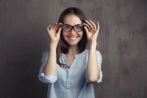 Portret van lachende vrouw met bril in de buurt van grijze achtergrond muur — Stockfoto