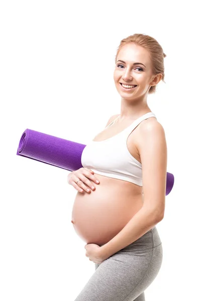 Kobieta w ciąży, trzymając matę do ćwiczeń fioletowy — Zdjęcie stockowe