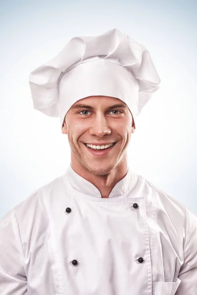 Standing smiling male cook in white uniform and hat — Stock Photo, Image