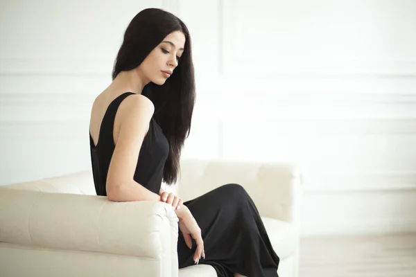 Elegante mujer sentada en un sofá de cuero blanco — Foto de Stock
