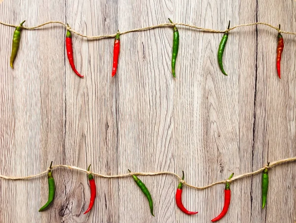 Bright background with peppers hanging on twine. Flat lay, view from above, wooden background Stock Picture