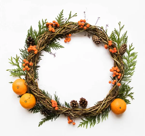 Corona festiva de viñas con mandarinas, ramas de thuja, rowanberries y conos. Piso tendido, vista superior — Foto de Stock