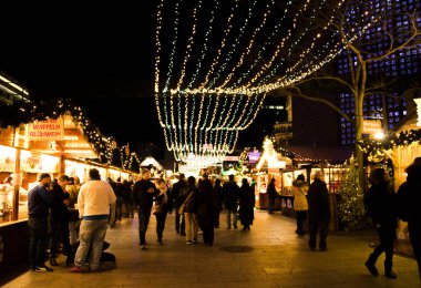 Berlin ufuk Noel Pazar geceleri. İnsanlar yemek ve dekore edilmiş semt pazarı ile yürüyüş