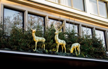 Geyikler ayakta yeşil Noel ağaçları arasında altın heykelleri. Reindeers üzerinde bir çatı ile şehir dekorasyon