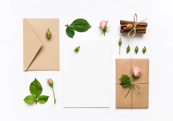 Letter, envelope and gift on white background. Invitation cards, or love letter with pink roses. Holiday concept, top view, flat lay — Stock Photo, Image