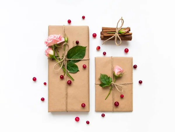 Presentförpackning och kuvert i eco papper på vit bakgrund. Presenterar dekorerad med rosor och bär. Holiday koncept, ovanifrån, platt låg — Stockfoto