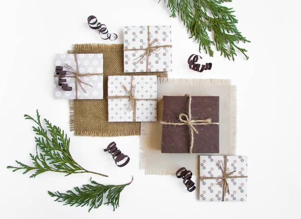 Rustikale handgefertigte Geschenkboxen auf weißem Hintergrund mit Zweigen dekoriert. Draufsicht, flache Lage — Stockfoto