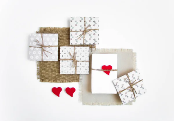 Caixas de presente artesanais rústicas sobre fundo branco decorado com corações. Vista superior, flat lay — Fotografia de Stock