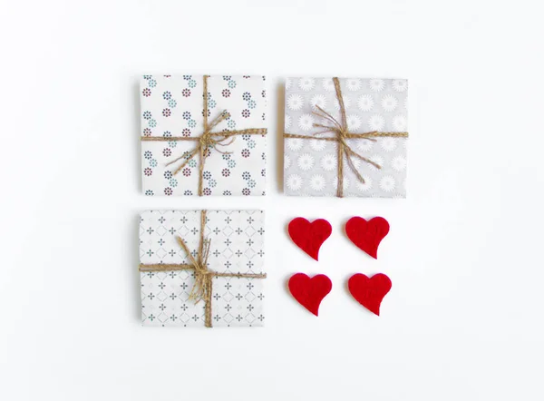 Rustikale handgefertigte Geschenkboxen mit Herzen auf weißem Hintergrund verziert. Draufsicht, flache Lage — Stockfoto