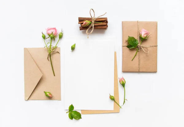 Brief, Umschlag und Geschenk auf weißem Hintergrund. Einladungskarten oder Liebesbriefe mit rosa Rosen. Urlaubskonzept, Draufsicht, flache Lage — Stockfoto