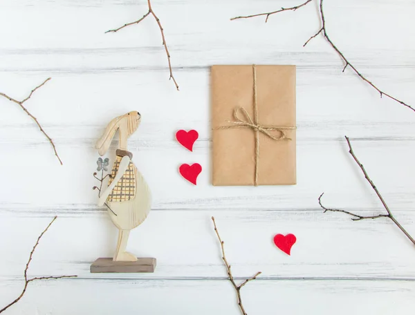 Vintage-Geschenk und Holzkaninchen auf weißem Tisch. Geschenke zum Valentinstag mit Ästen. Draufsicht, flache Lage — Stockfoto