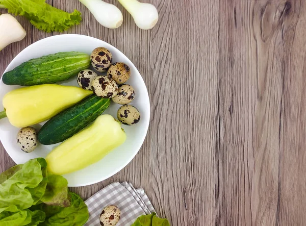 Composición colorida con verduras y huevos de codorniz en un plato sobre fondo de madera. Piso tendido, vista superior — Foto de Stock