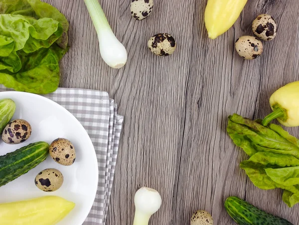 Colorful composition with vegetables and quail eggs on a plate on wooden background. Flat lay, top view — Stock Photo, Image