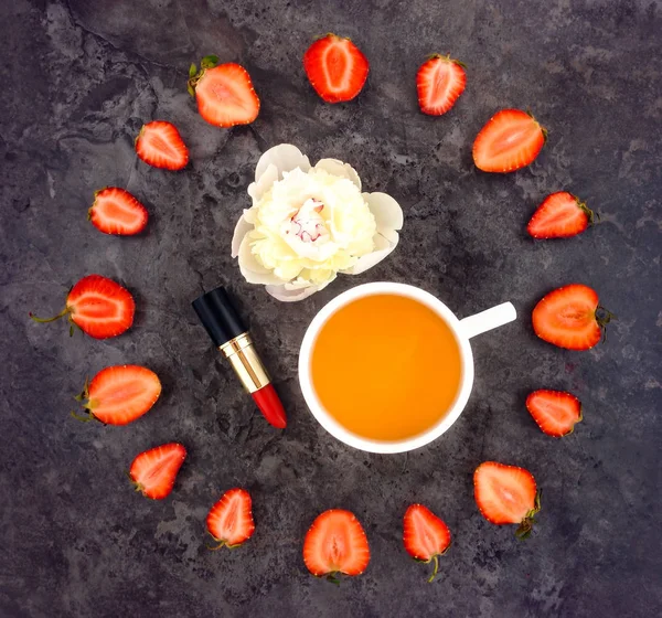 Colorida composición brillante de la taza de té, fresas, lápiz labial y flor de peonía — Foto de Stock